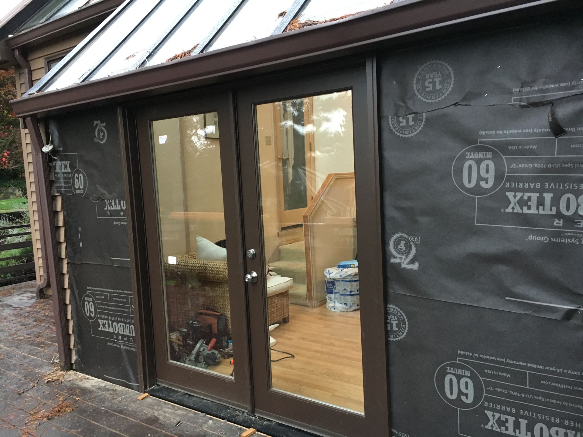 Brown framed French doors and windows on a building, covered in black sheathing.