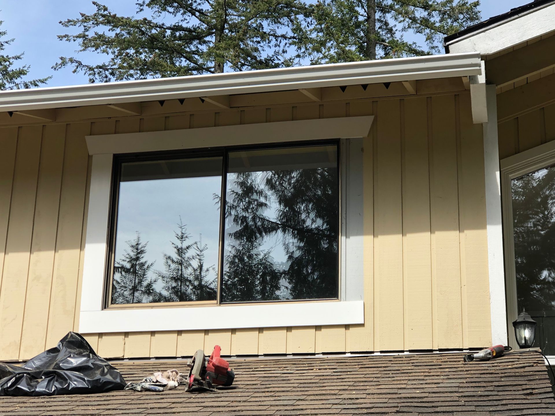 Yellow house exterior with a sliding glass window. Reflection of trees in window.