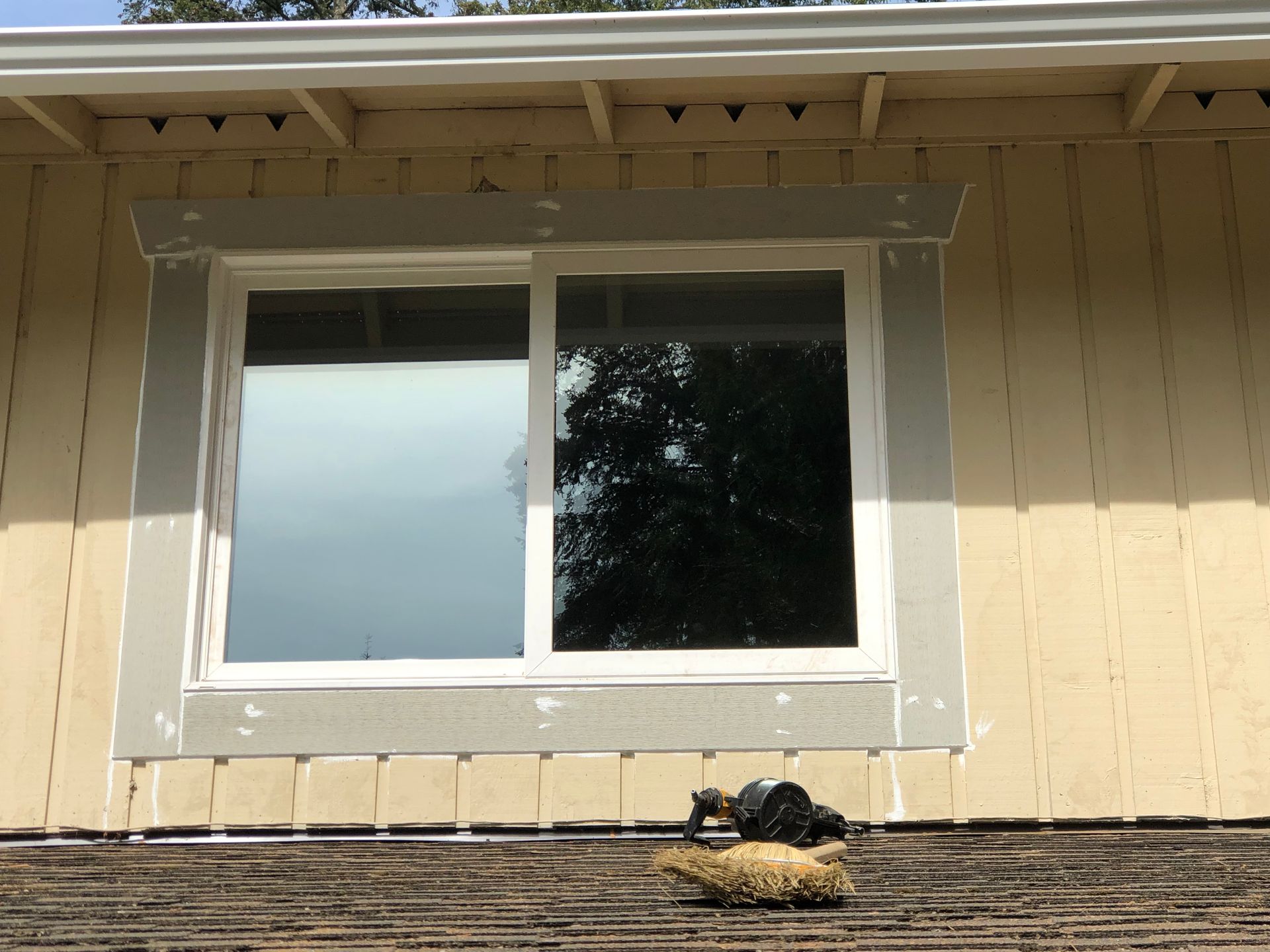 A window on a yellow house with white trim and gray accents.