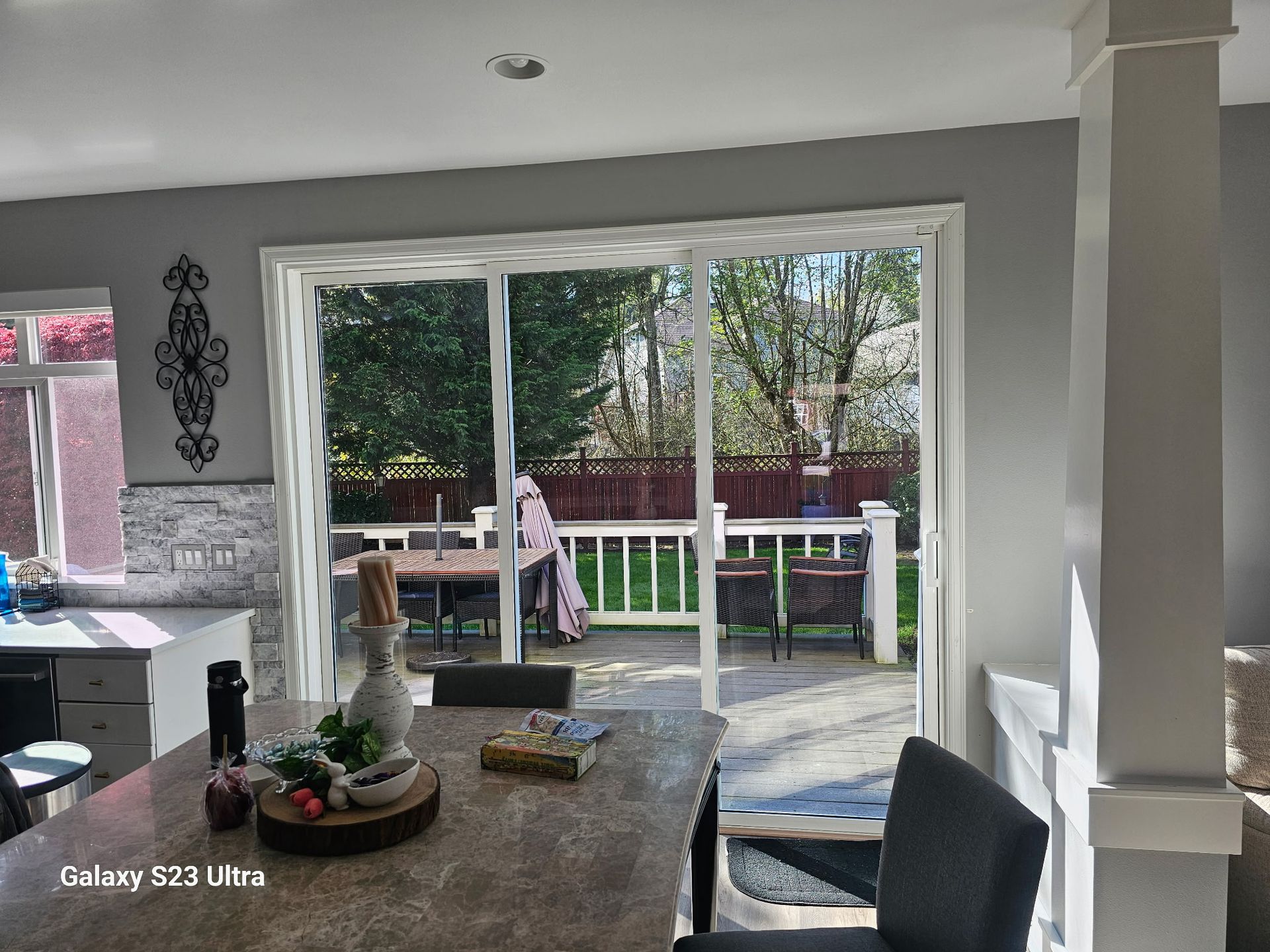 Kitchen with sliding glass door to a backyard deck. Table set with decor. Bright natural light.