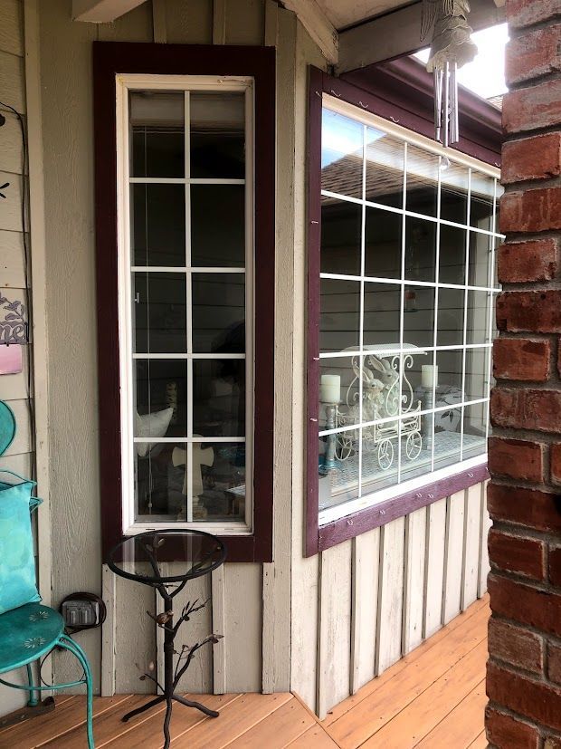 Two windows with white grids and burgundy frames on a light-colored house exterior.