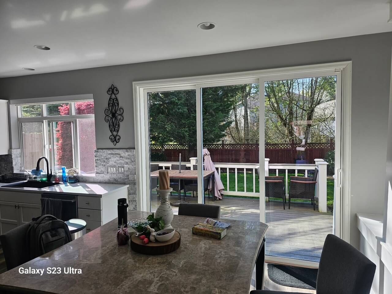 Kitchen interior with a sliding glass door leading to a patio. Sunlight, stone countertop.