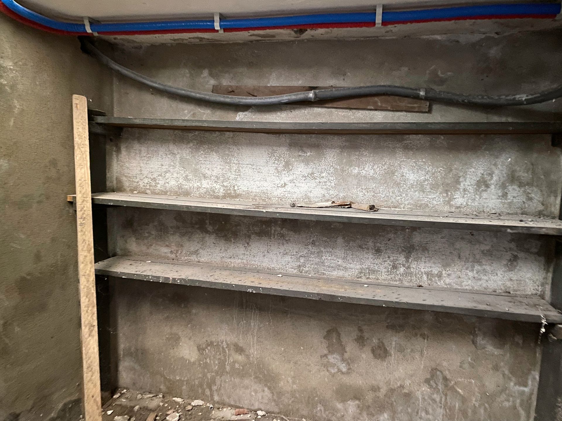 There are three shelves in the corner of a basement room.