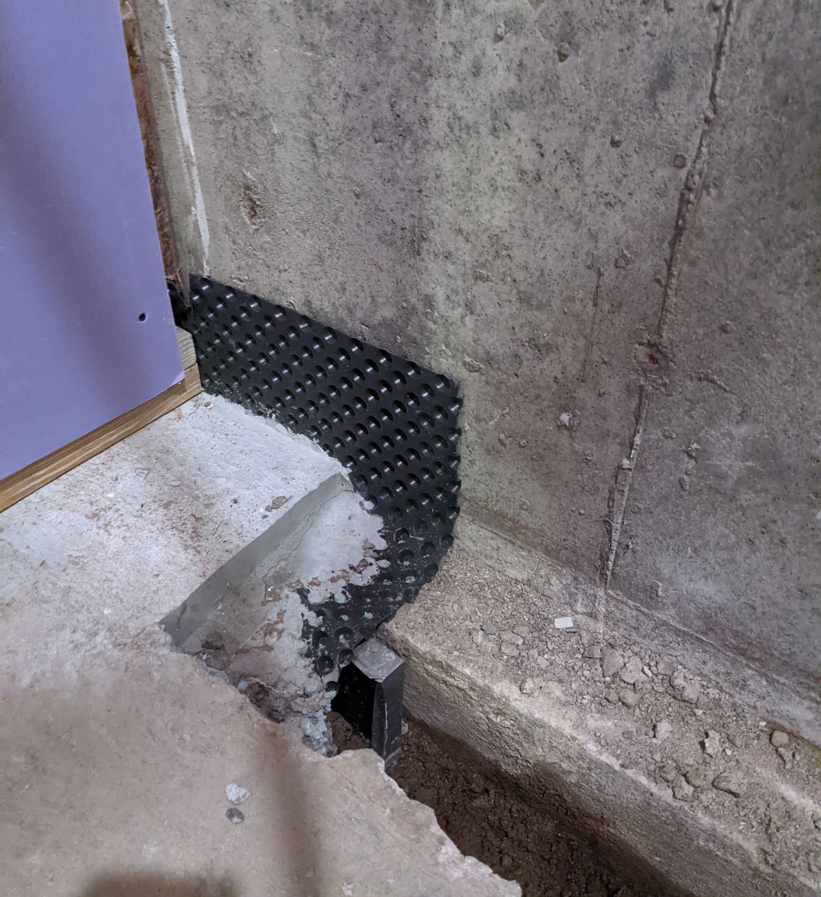 a corner of a concrete wall with a piece of rubber on it for waterproofing the basement of a house