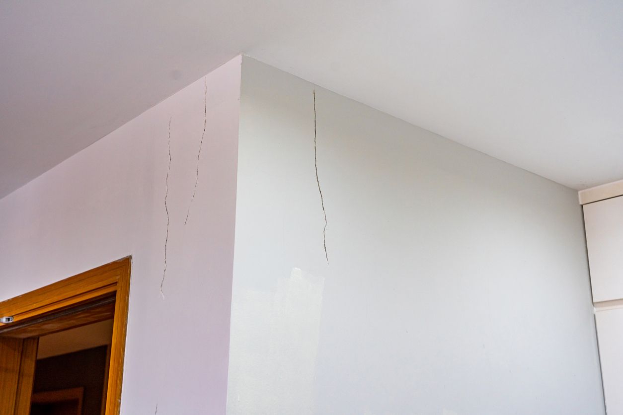 a corner of a room with a door and a white wall showing a crack from an unstable foundation