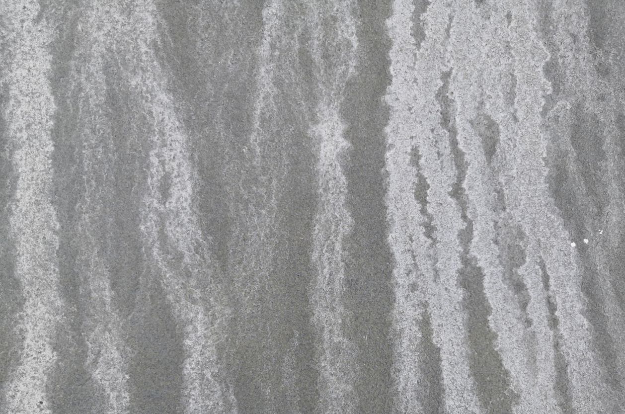 a close up of a gray surface with a grainy texture showing water stains