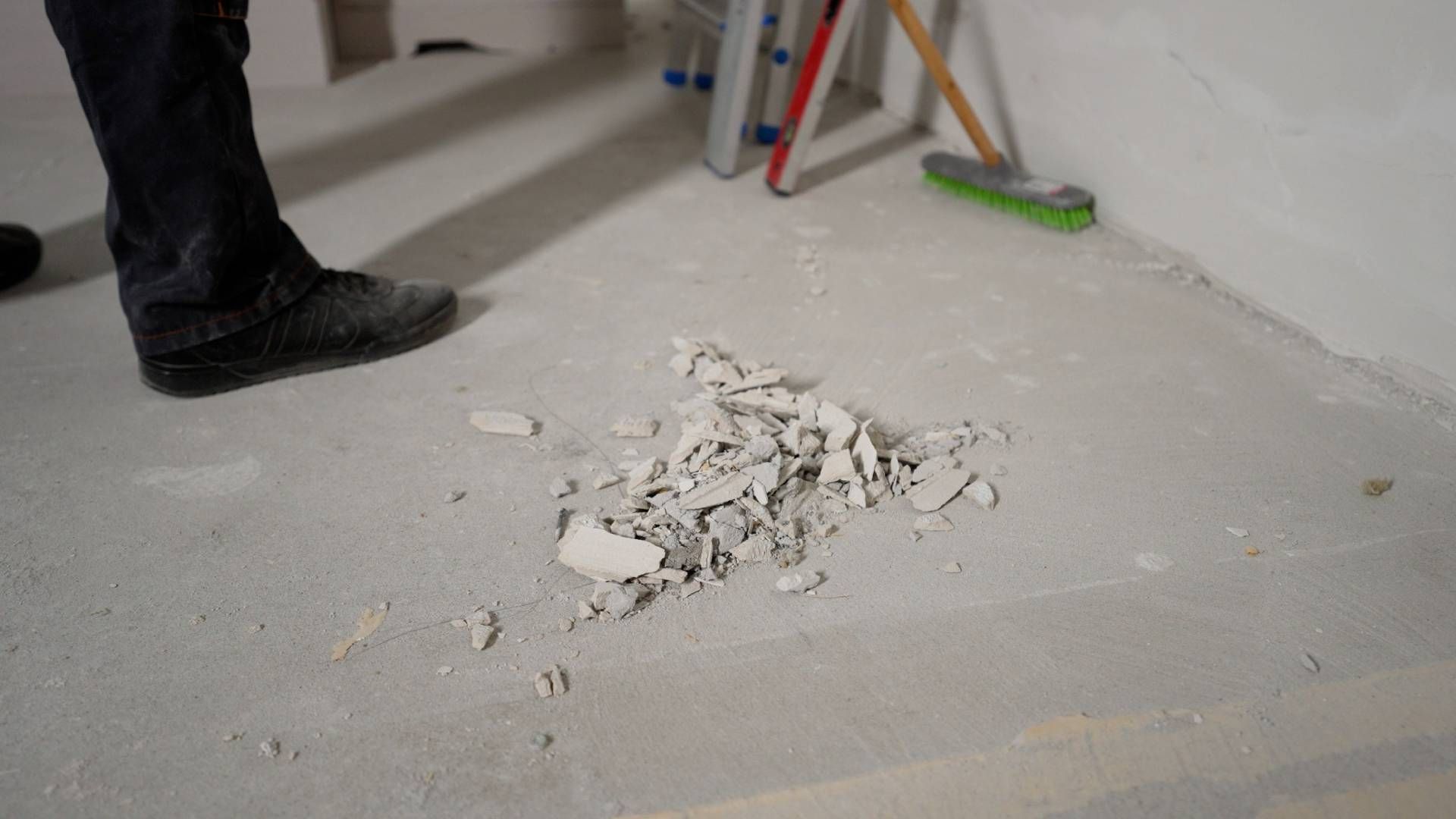 Person standing near a pile of debris on a concrete floor. Construction site.