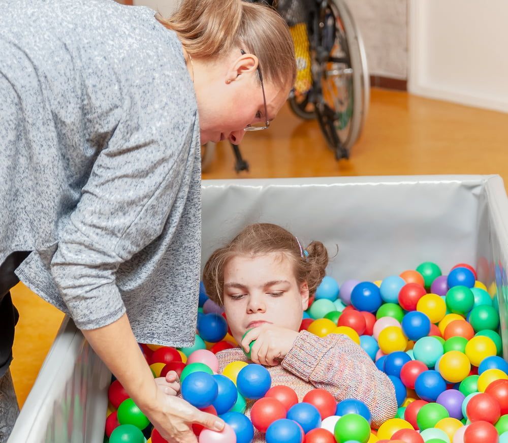 A Woman Is Playing with A Child in A Ball Pit — VAL Disability Services in Taree, NSW