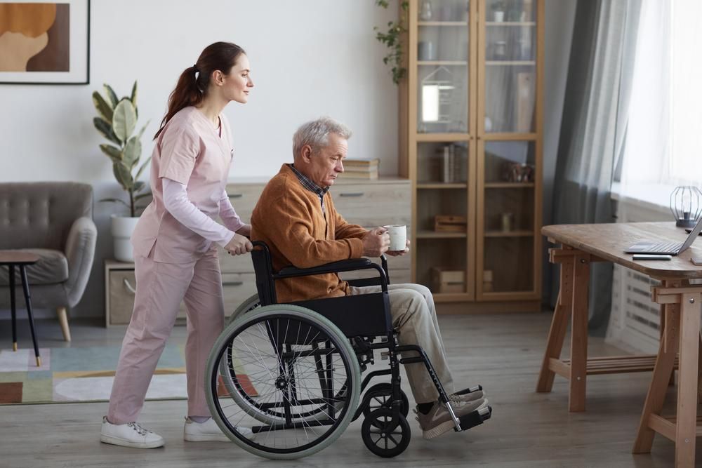 Woman Assisting Old Man On A Wheel Chair — VAL Disability Services in Taree, NSW
