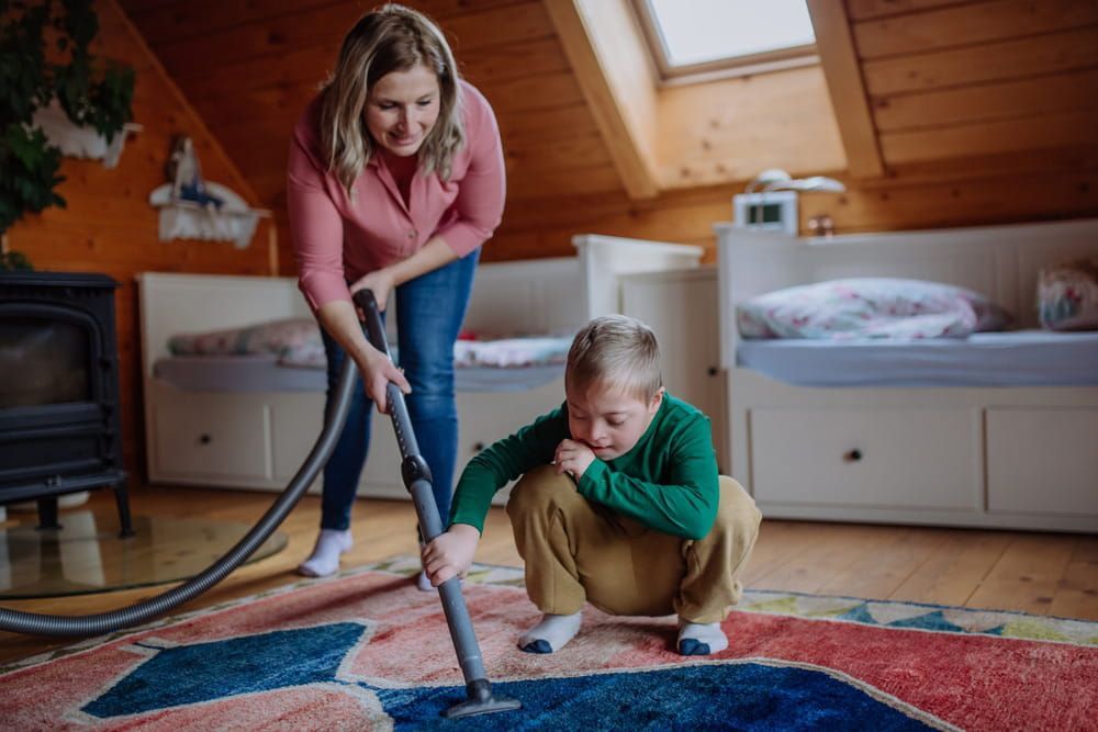 A Woman and A Boy Are Cleaning a Rug with A Vacuum Cleaner — VAL Disability Services in Taree, NSW