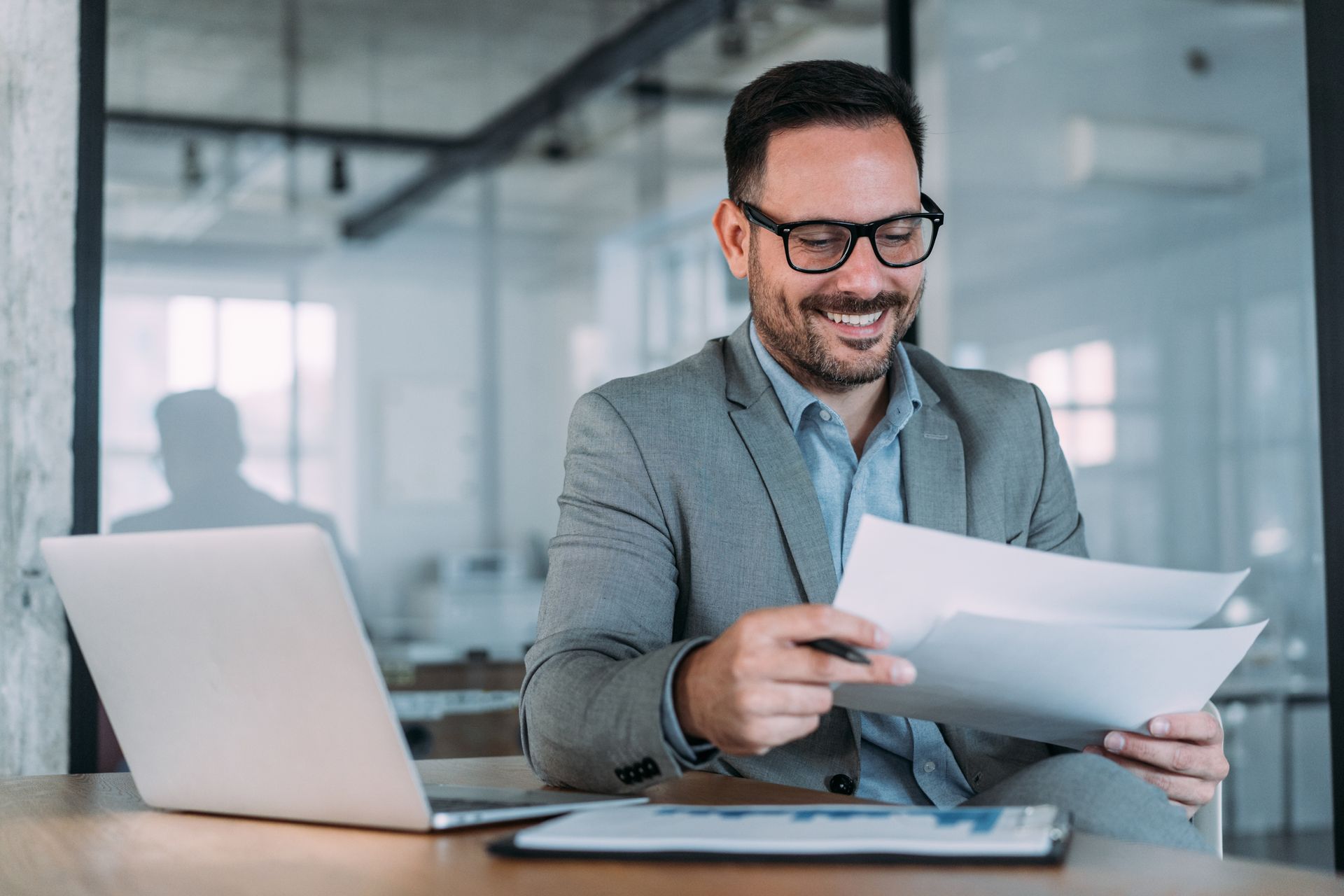 A man is sitting at a desk with a laptop and a piece of paper.