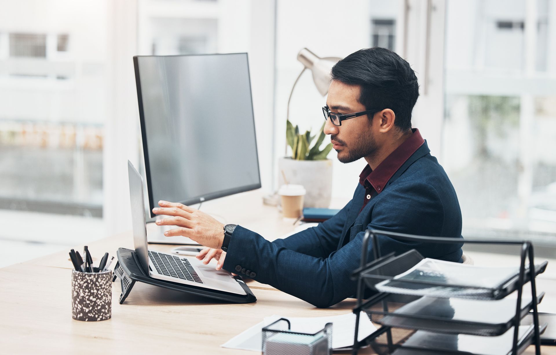 A man is sitting at a desk using a laptop computer.