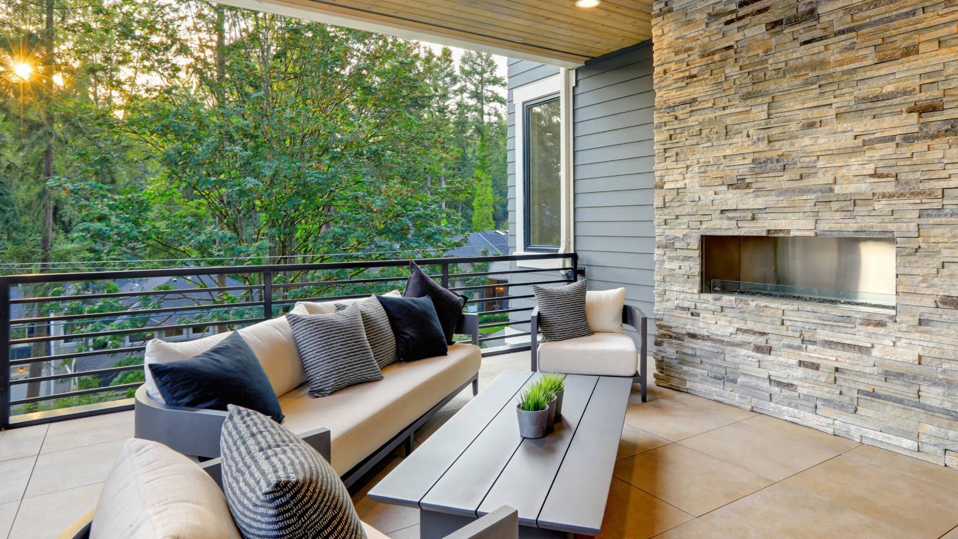 A patio with a couch , chairs , table and fireplace.