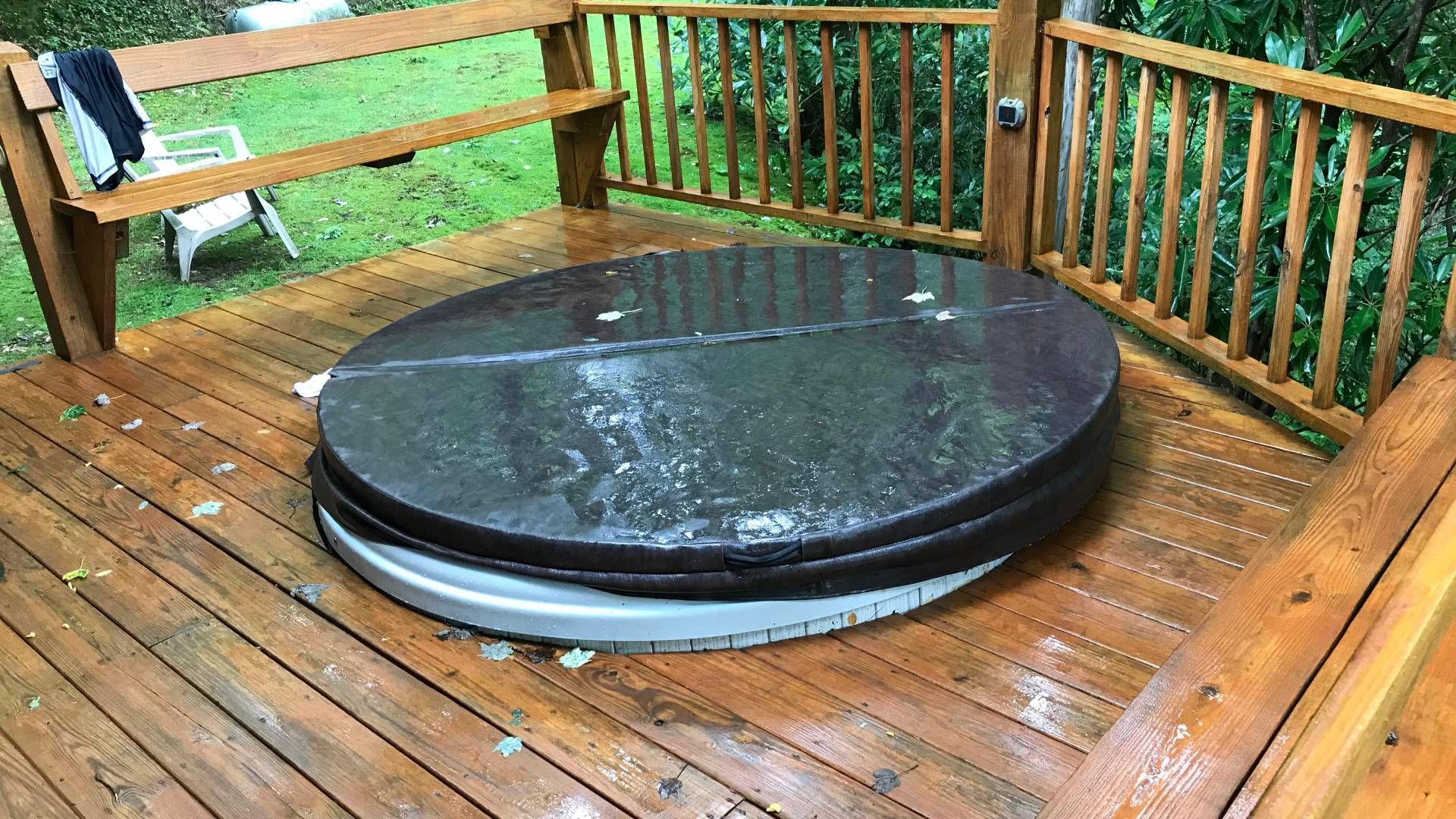 A round hot tub is sitting on top of a wooden deck.