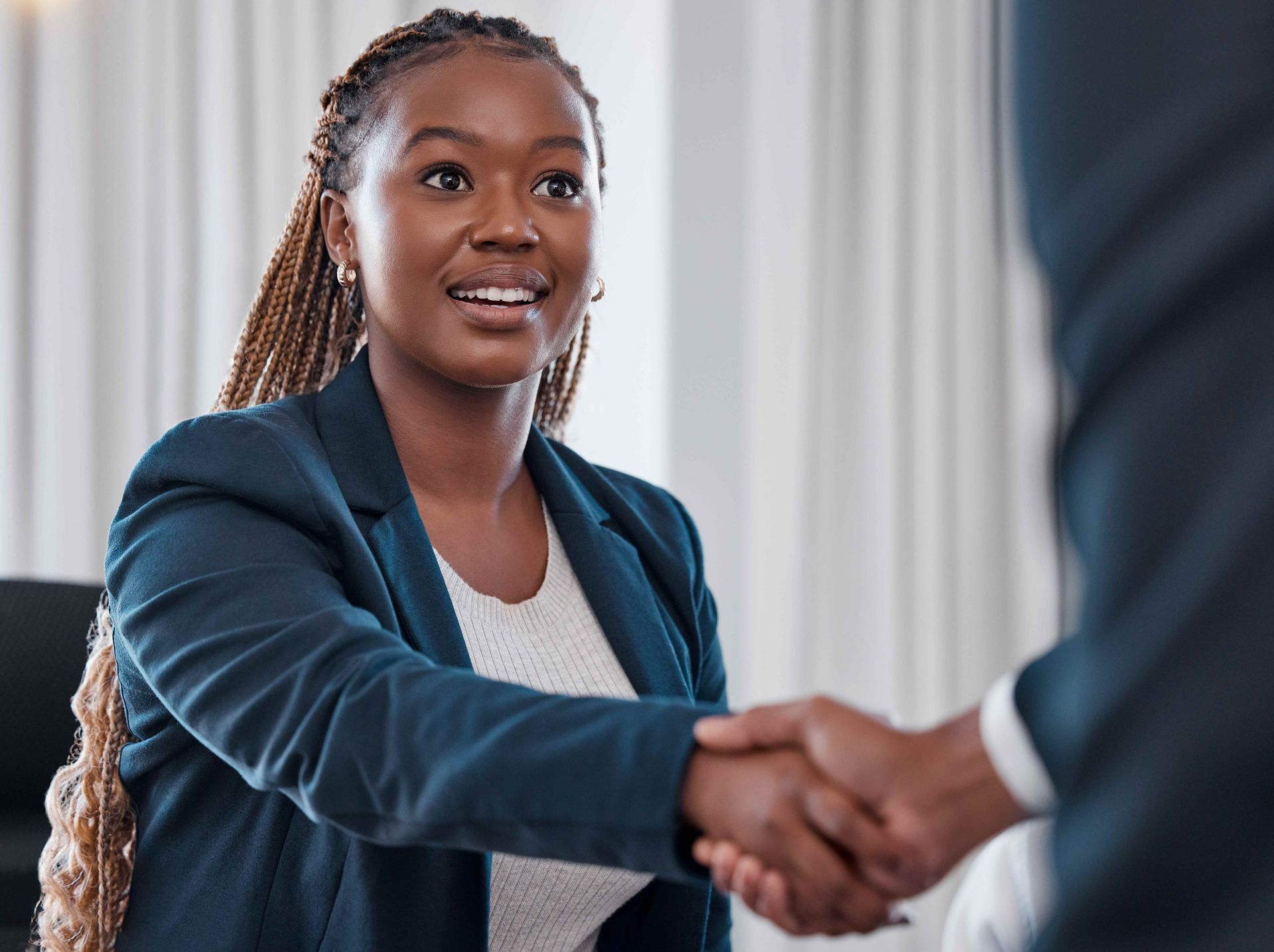 a woman in a blue jacket is shaking hands with a man in a suit