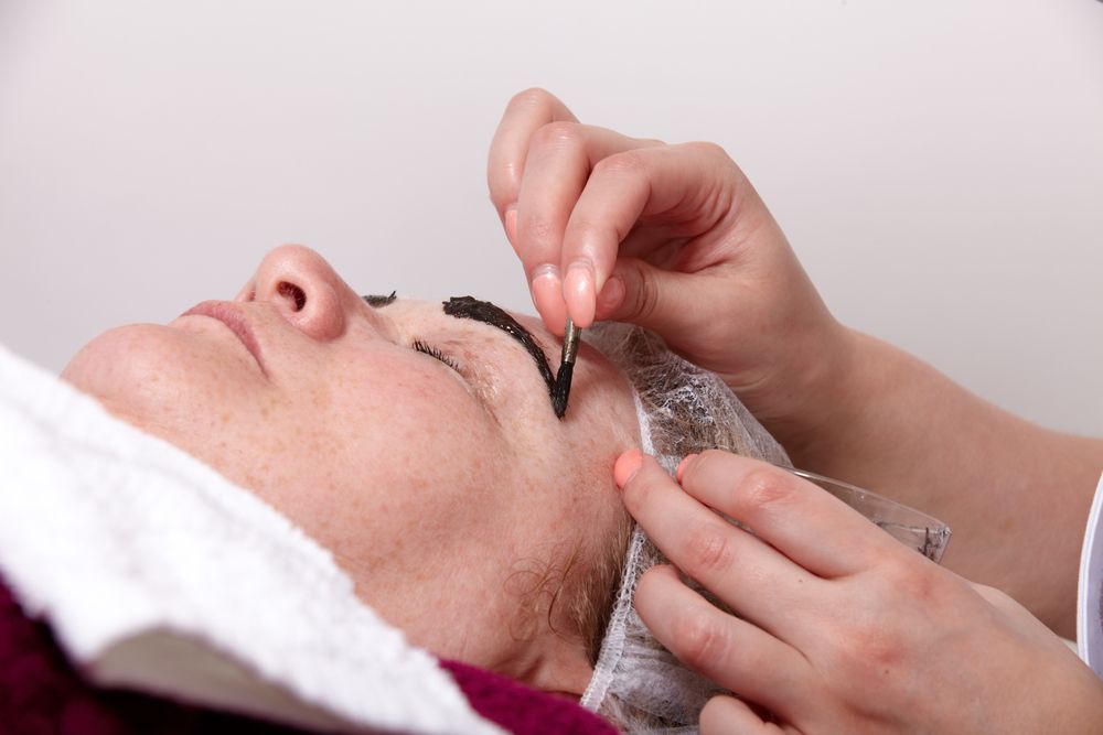 A woman is getting her eyebrows painted in a beauty salon.