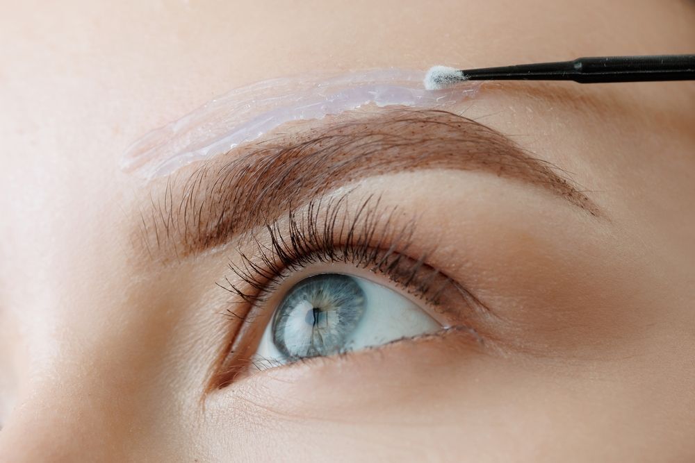 A woman is getting her eyebrows painted with a brush.