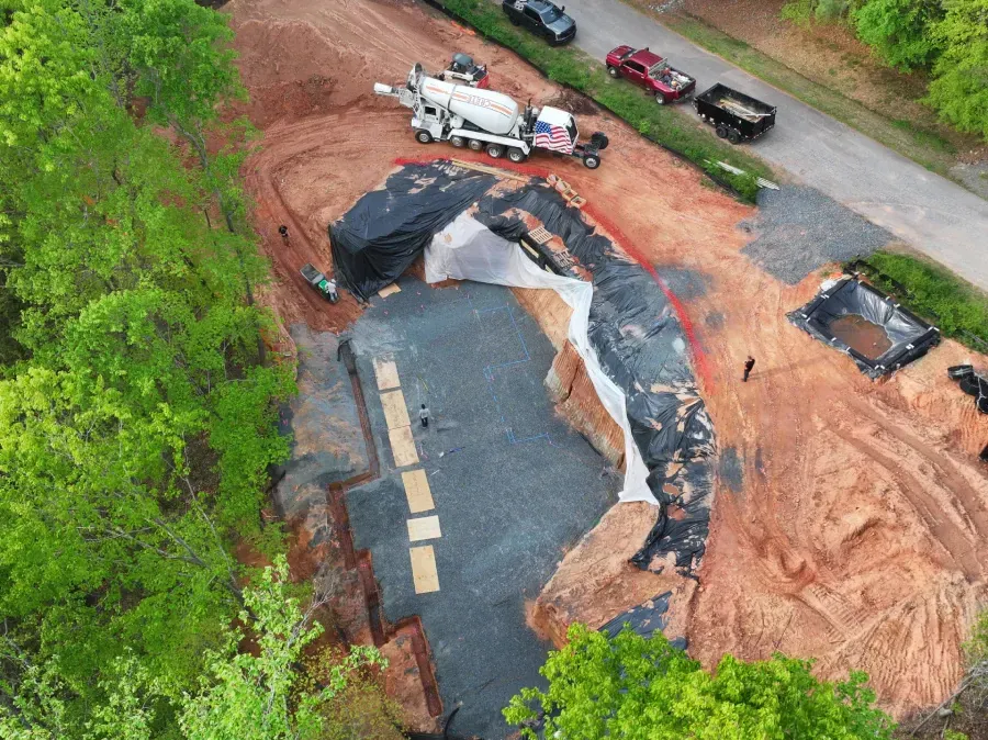 Aerial view of a collapsed road and landslide with emergency vehicles nearby in a wooded area