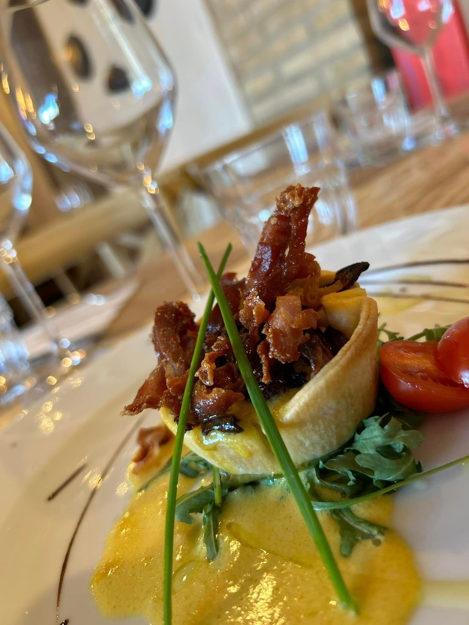 Un primo piano di un piatto di cibo su un tavolo con un bicchiere di vino sullo sfondo.