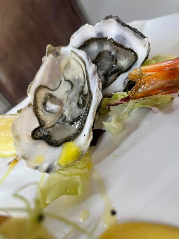 Un piatto bianco con sopra ostriche e lattuga