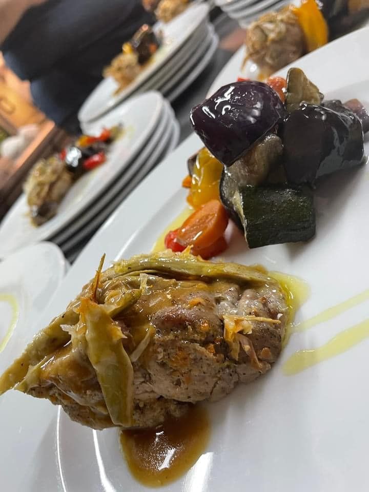 Un piatto bianco con un pezzo di carne e verdure sopra