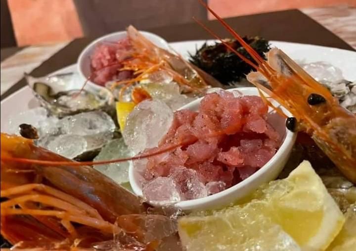 Un piatto di frutti di mare con ghiaccio e fette di limone su un tavolo.