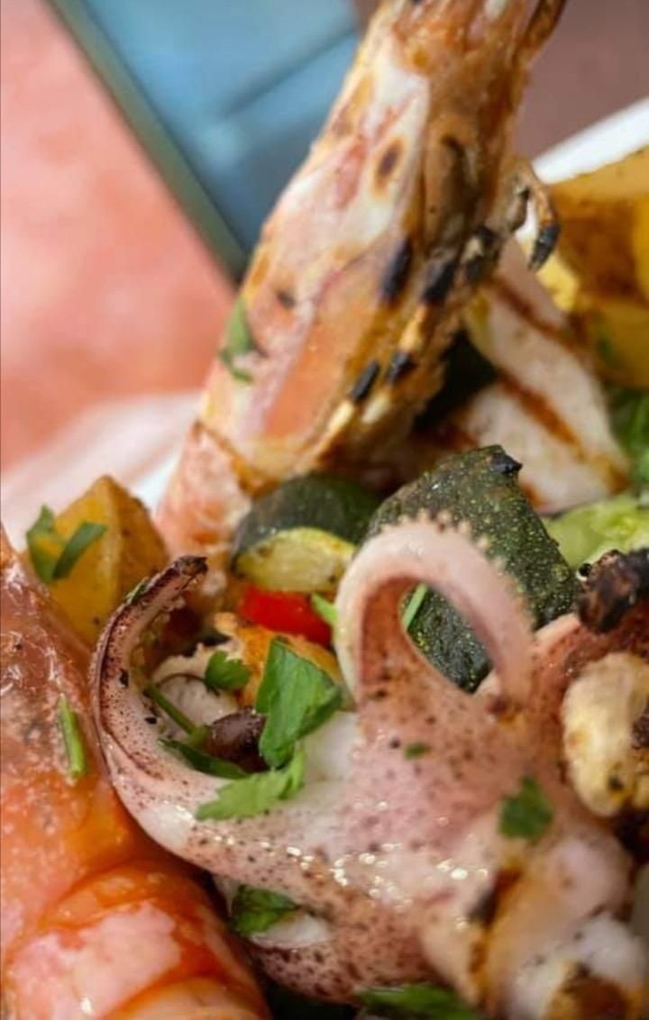 Un primo piano di un piatto di cibo con gamberi, calamari e patate