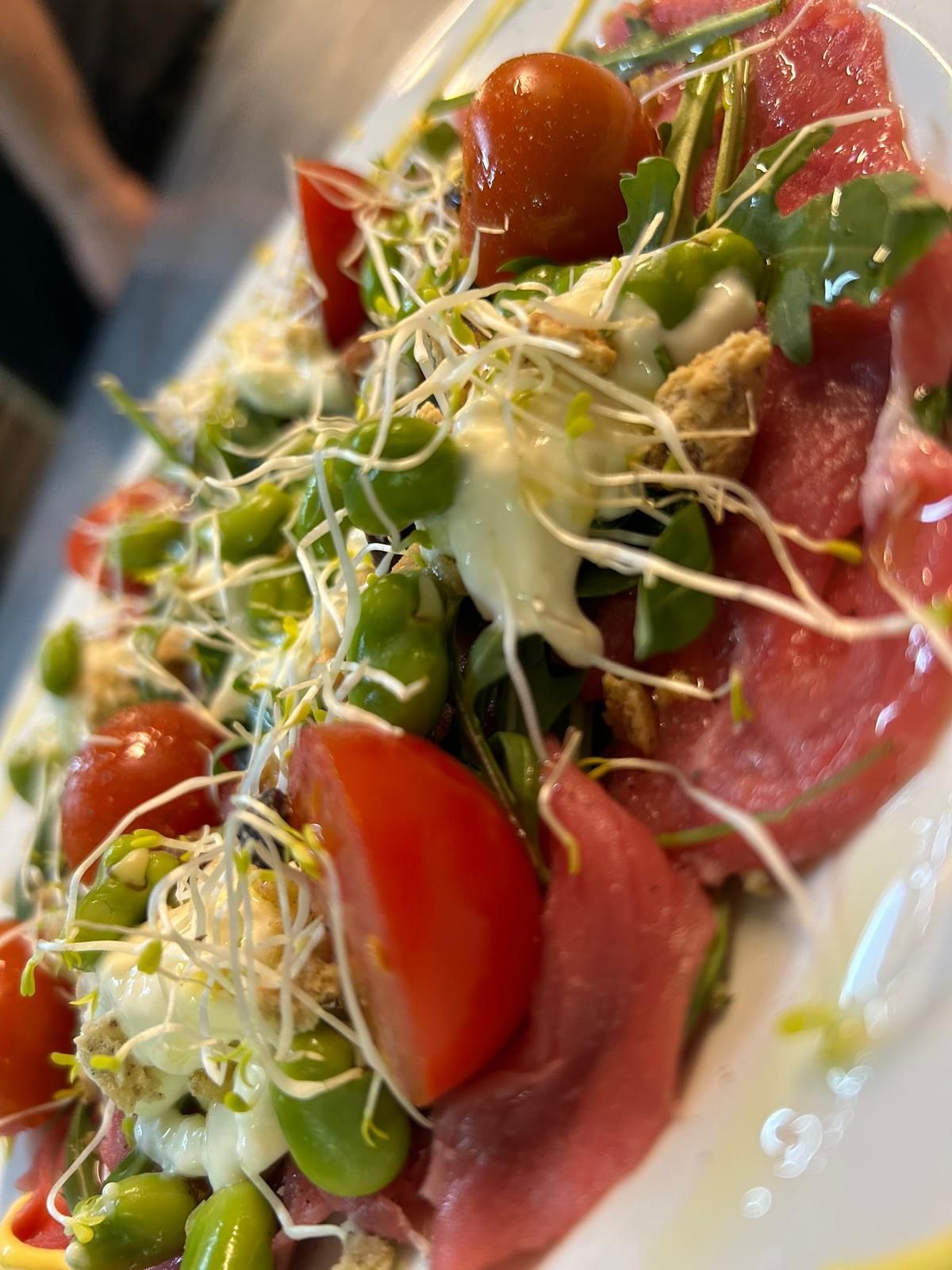 Un primo piano di un piatto di cibo con pomodori e germogli su un tavolo.