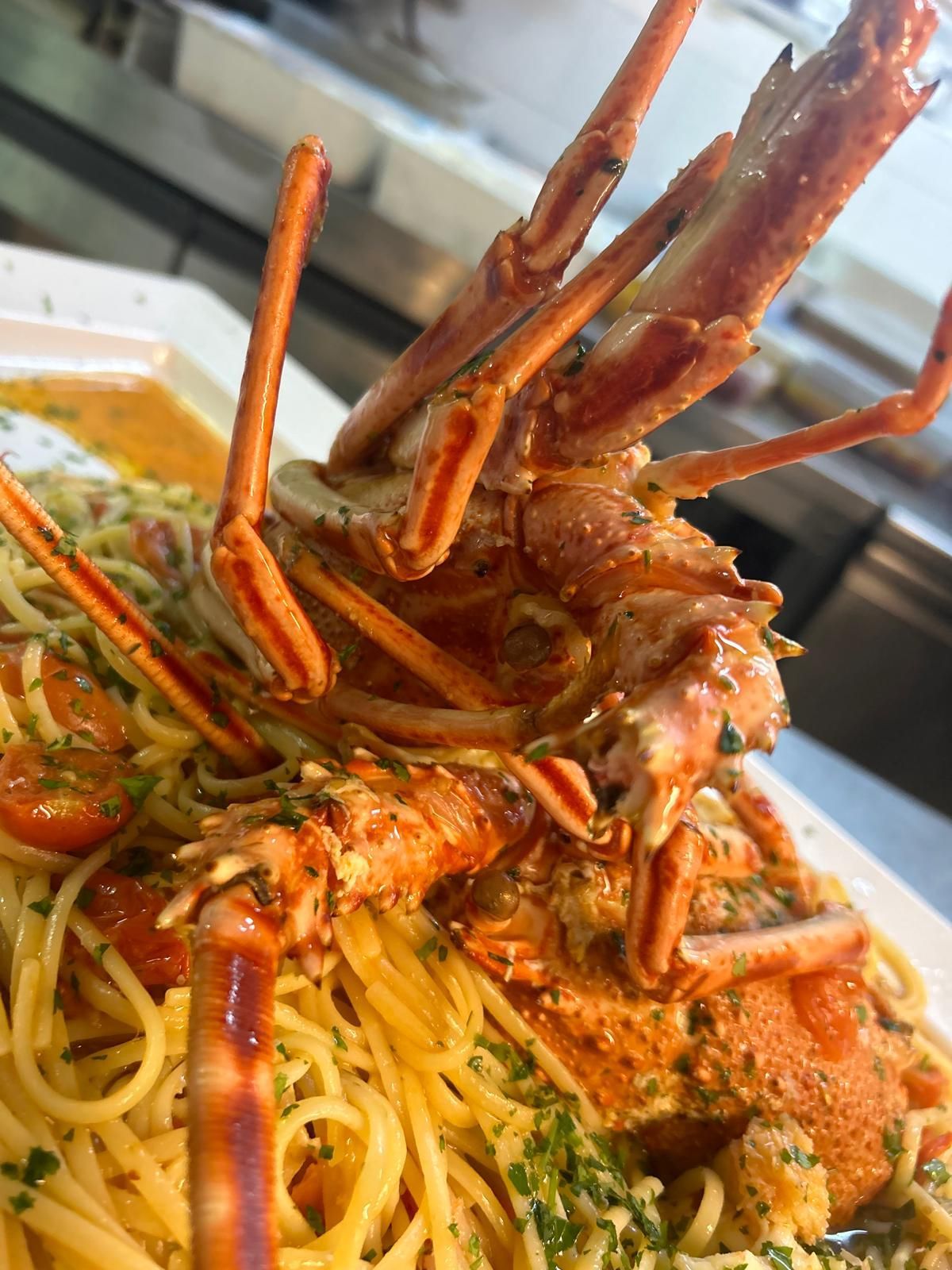 Una grande aragosta è appoggiata su un piatto di spaghetti.