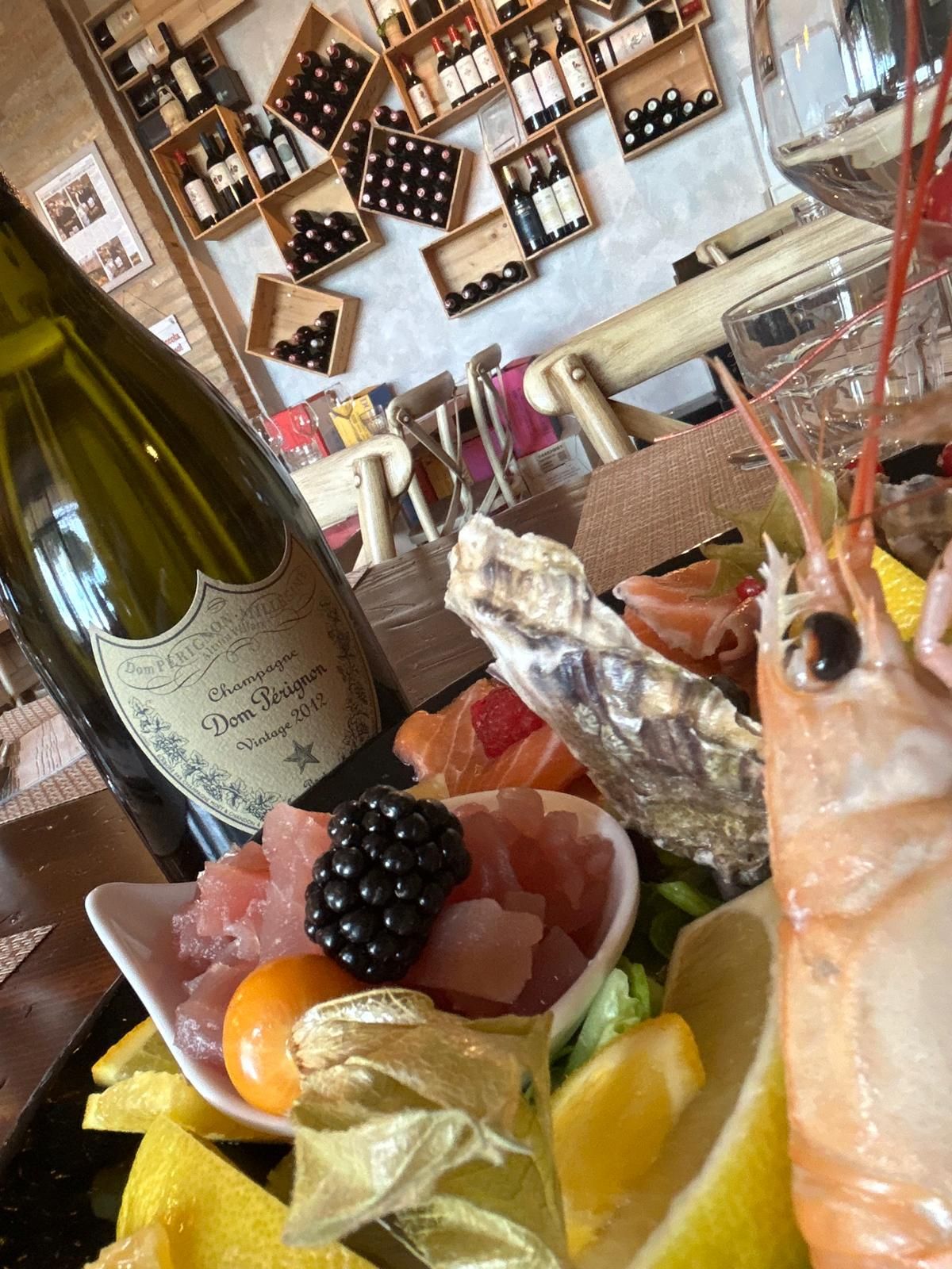 Una bottiglia di champagne è appoggiata accanto a un piatto di cibo.