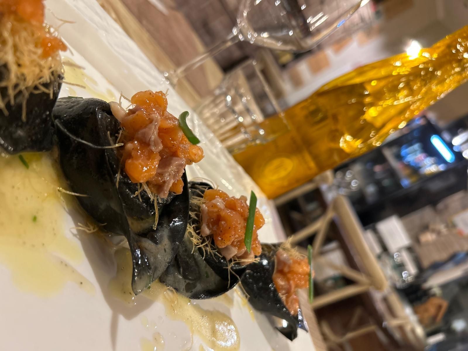 Un primo piano di un piatto di cibo con una bottiglia di champagne sullo sfondo.