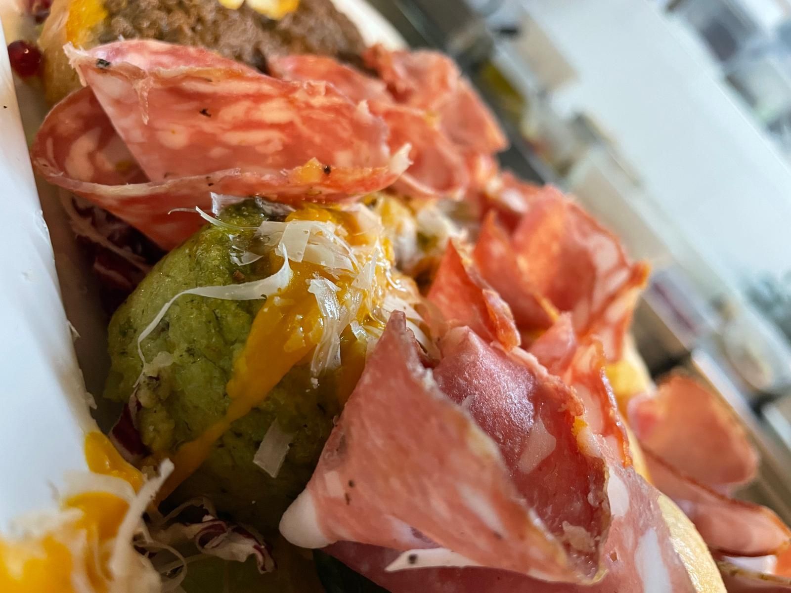 Un primo piano di un hot dog con carne e formaggio su un piatto.