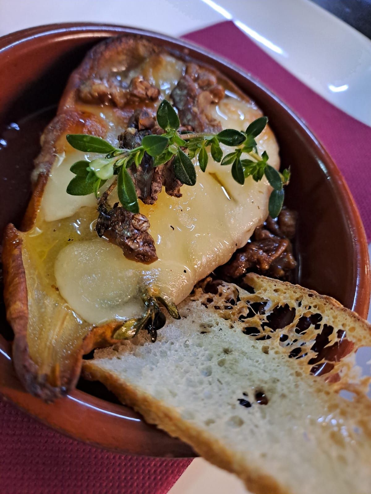 Un primo piano di una ciotola di cibo con una fetta di pane su un tavolo.