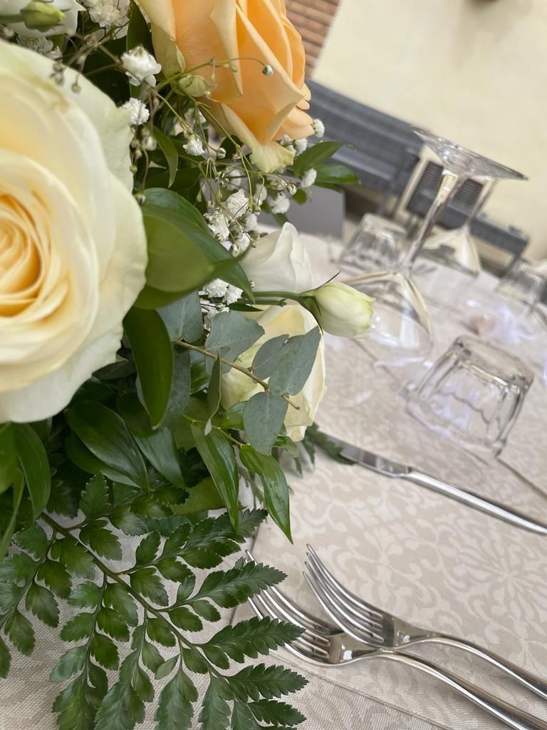 Un tavolo con sopra un mazzo di fiori e delle posate d'argento.