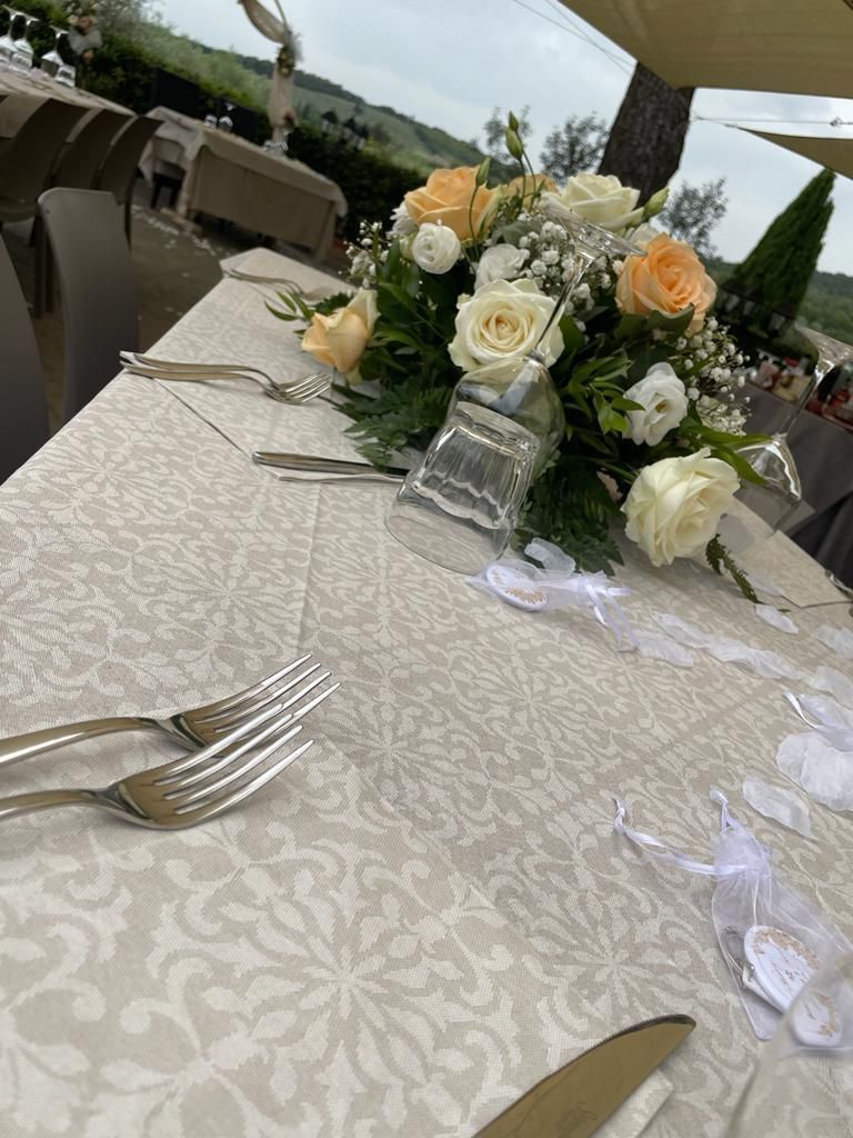 Un tavolo apparecchiato per un ricevimento di nozze con un mazzo di fiori sopra.