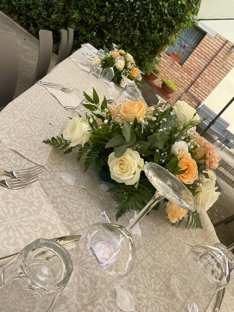 Un tavolo con sopra un vaso di fiori e bicchieri da vino.