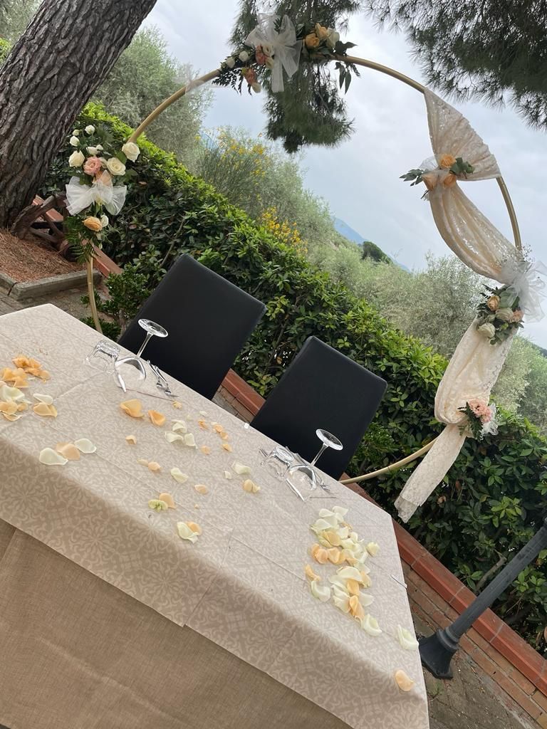 Un tavolo con fiori e bicchieri da vino davanti a un albero.