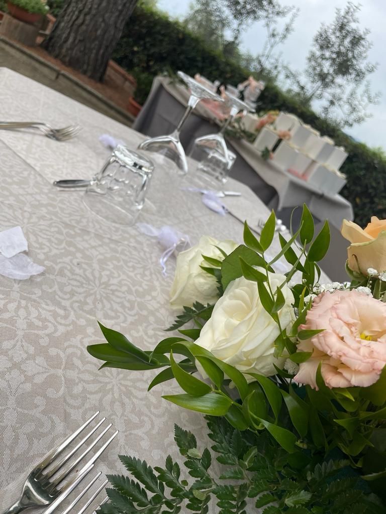 Un tavolo apparecchiato per un ricevimento di nozze con fiori e bicchieri sopra.