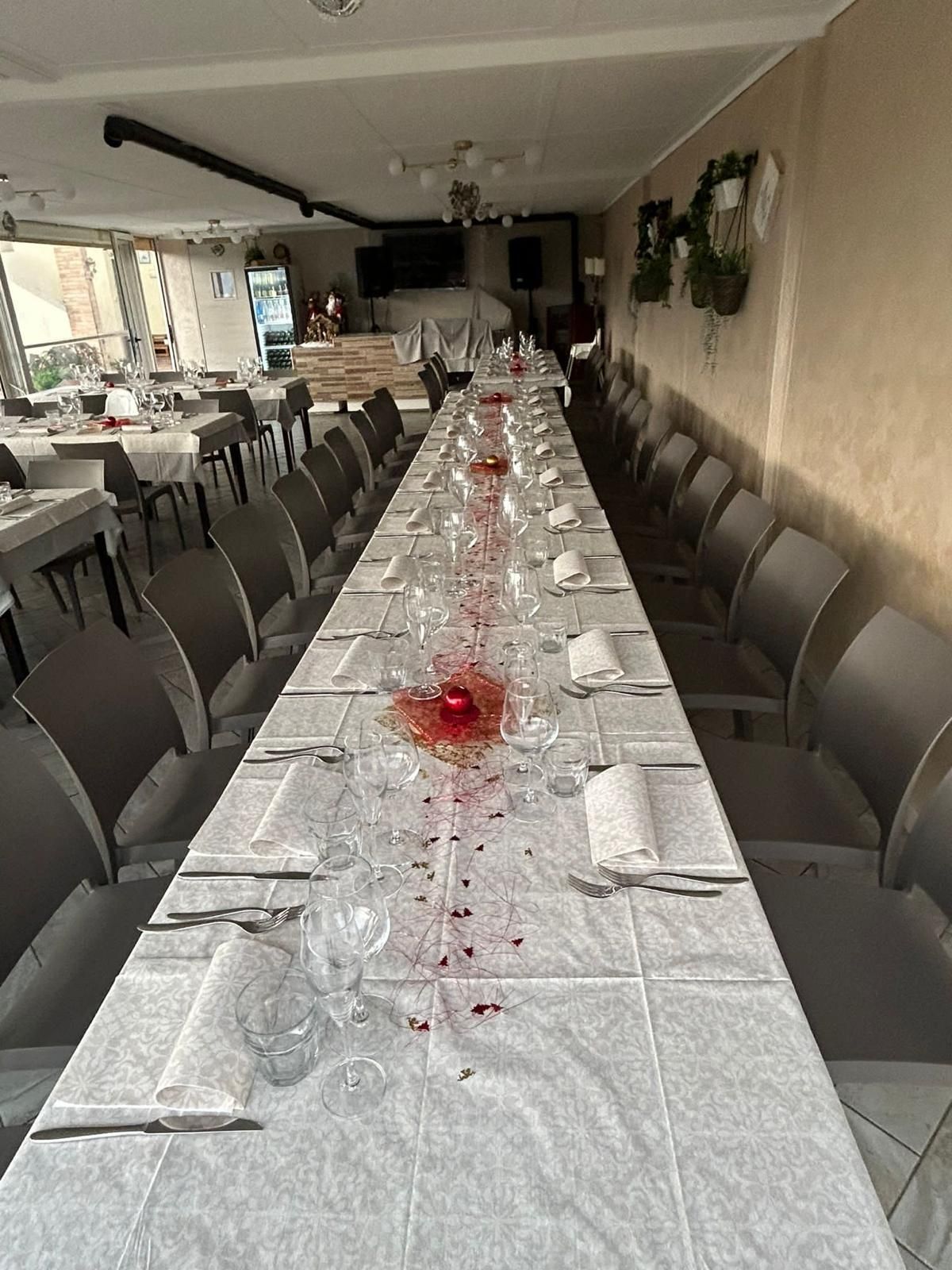 Un lungo tavolo con una tovaglia bianca e dei bicchieri in un ristorante.