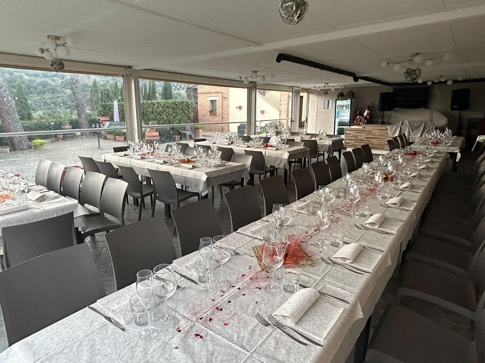 Un lungo tavolo con una tovaglia bianca e dei bicchieri in un ristorante.