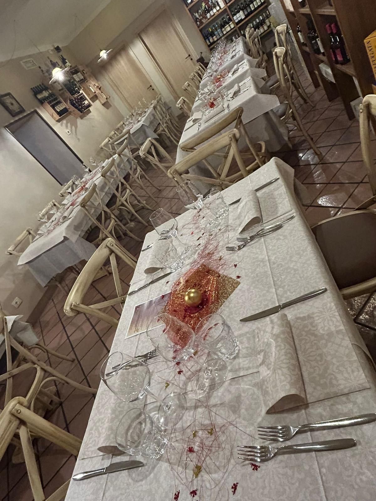 Un lungo tavolo con una tovaglia bianca e posate d'argento in un ristorante.