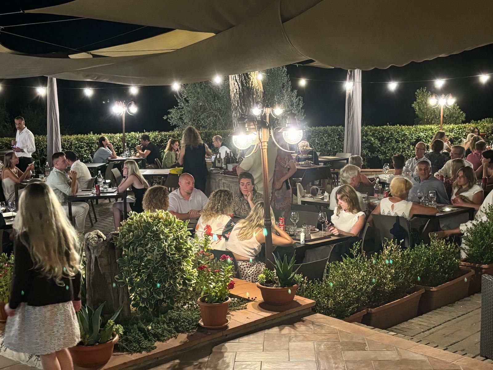 Un gruppo di persone è seduto ai tavoli di un ristorante di notte.