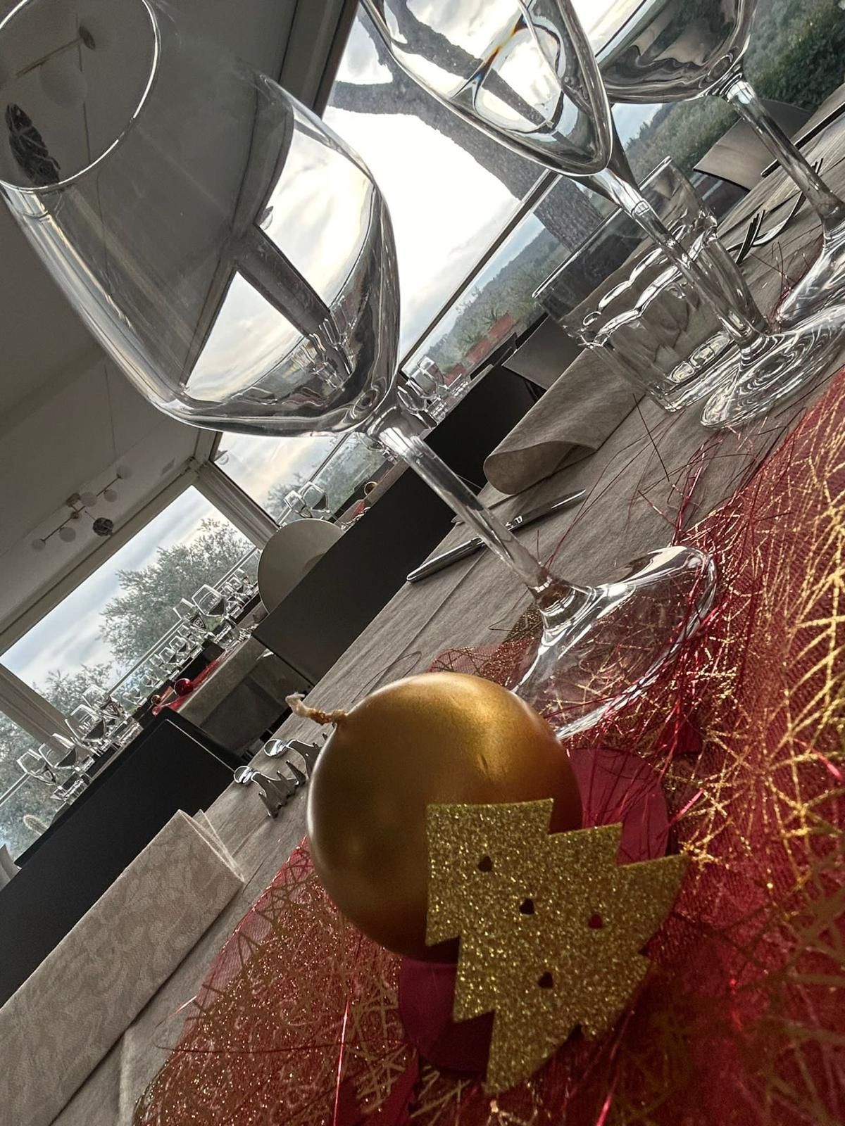 Due bicchieri da vino sono appoggiati su un tavolo accanto a un addobbo natalizio dorato.