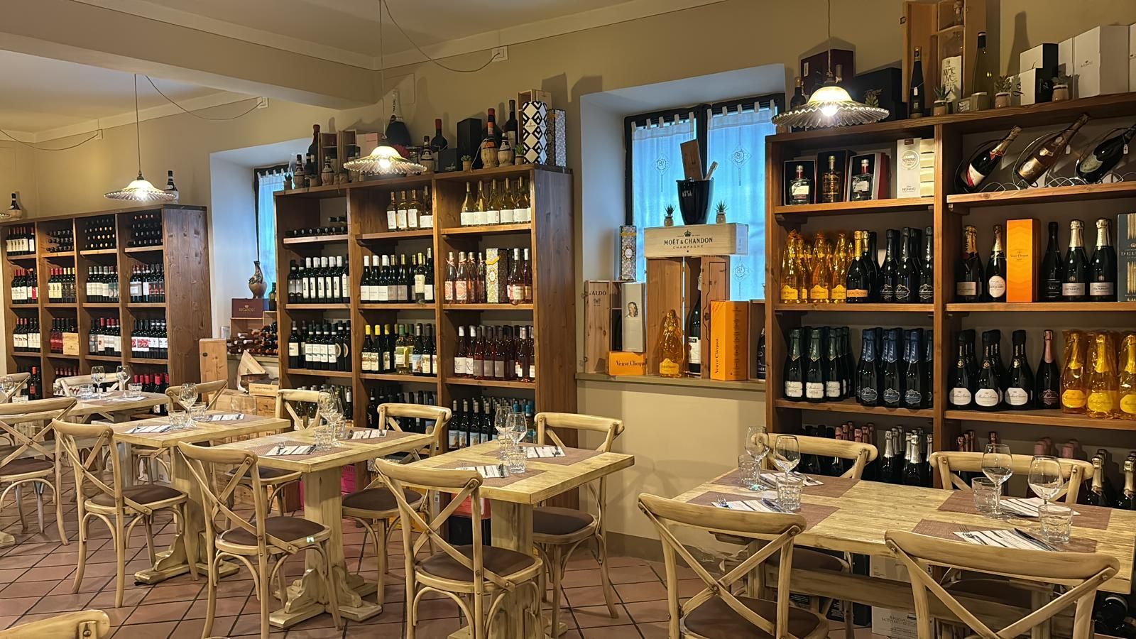 Un ristorante con tavoli, sedie e scaffali pieni di bottiglie di vino.
