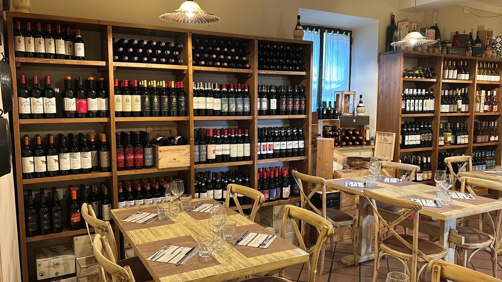 Un ristorante con tavoli, sedie e scaffali pieni di bottiglie di vino.
