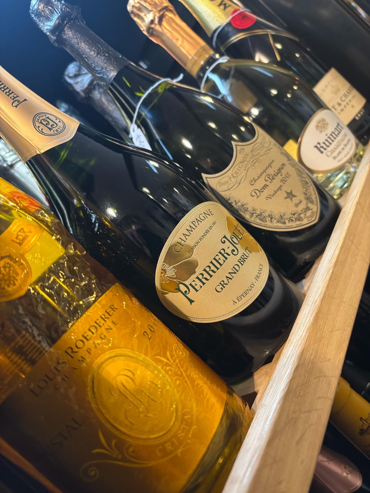 Diverse bottiglie di champagne sono allineate su uno scaffale di legno