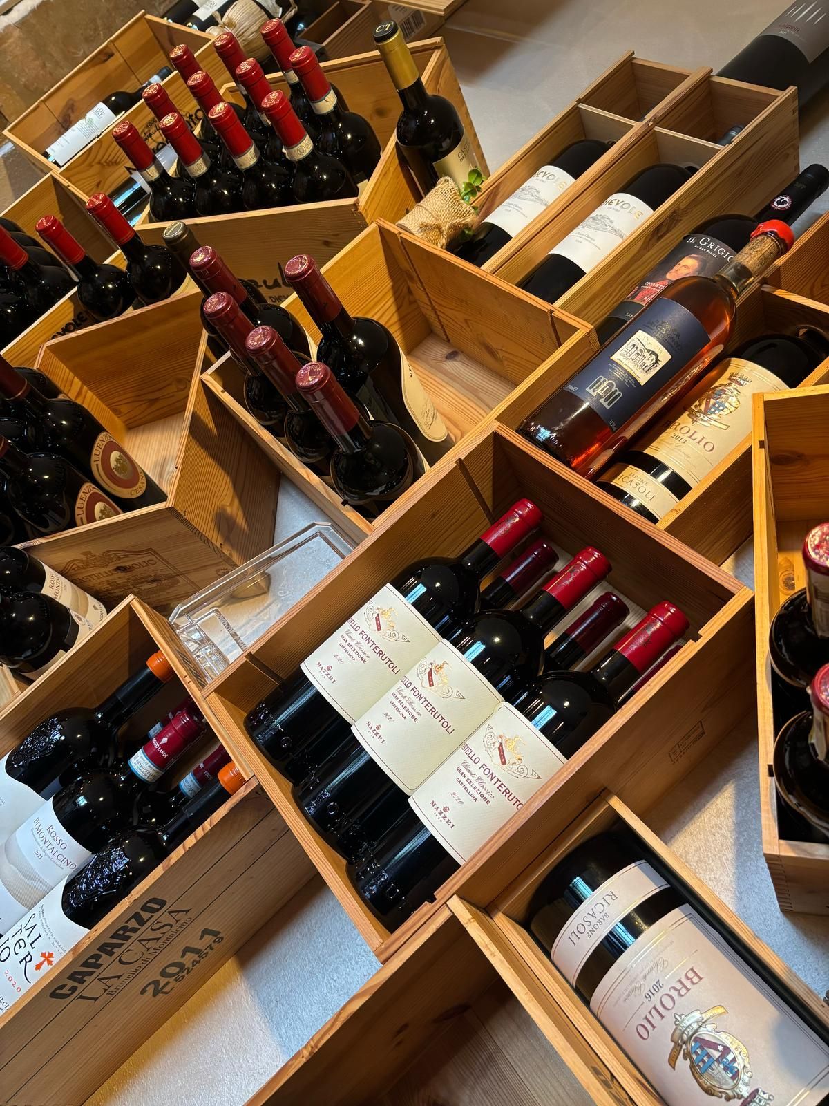 Un mucchio di bottiglie di vino sono in scatole di legno