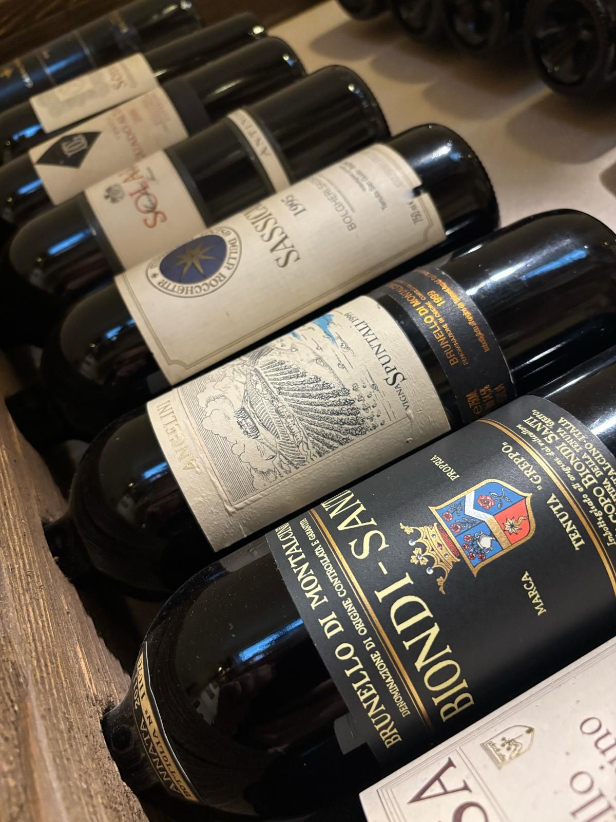 Una fila di bottiglie di vino sono allineate su uno scaffale.