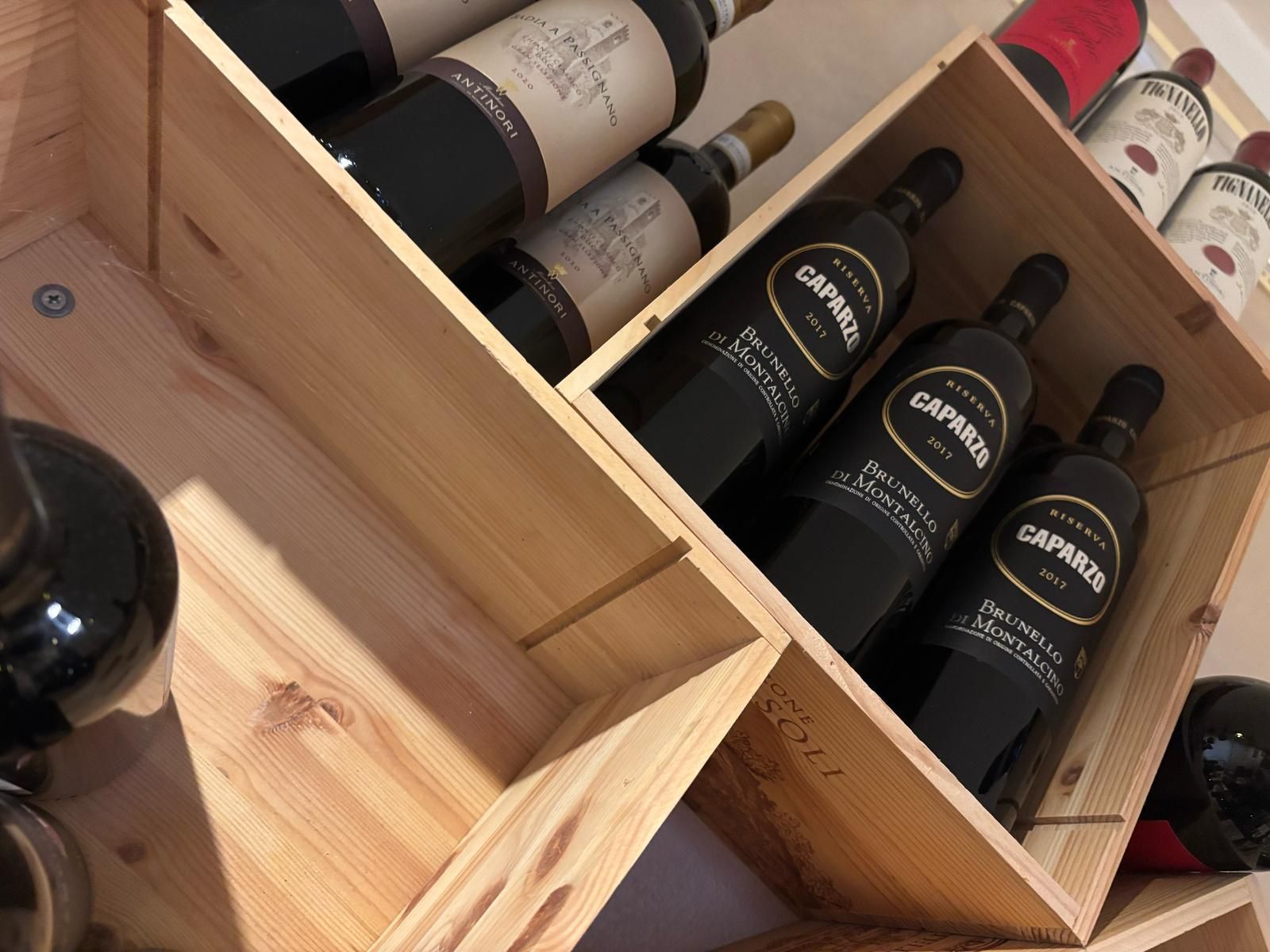 Una fila di scatole di legno piene di bottiglie di vino tra cui una bottiglia di garnera