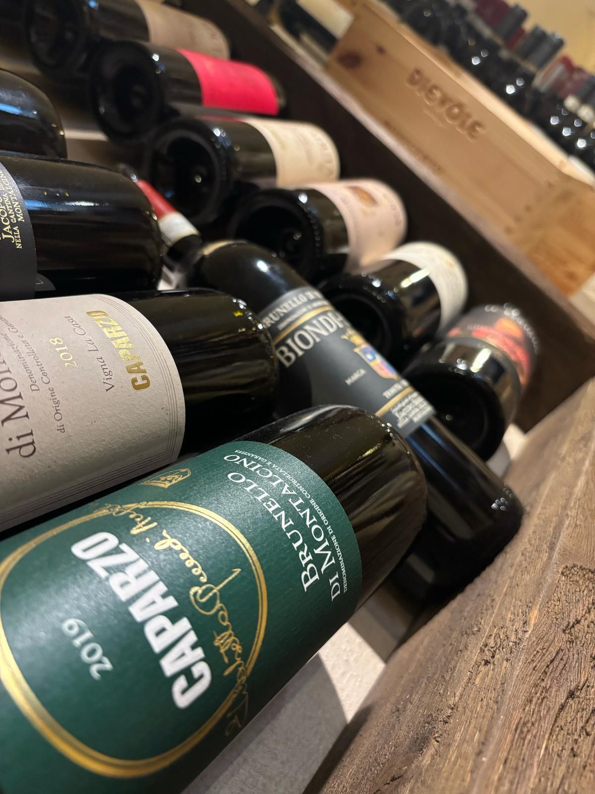 Diverse bottiglie di vino sono impilate l'una sull'altra su uno scaffale di legno.